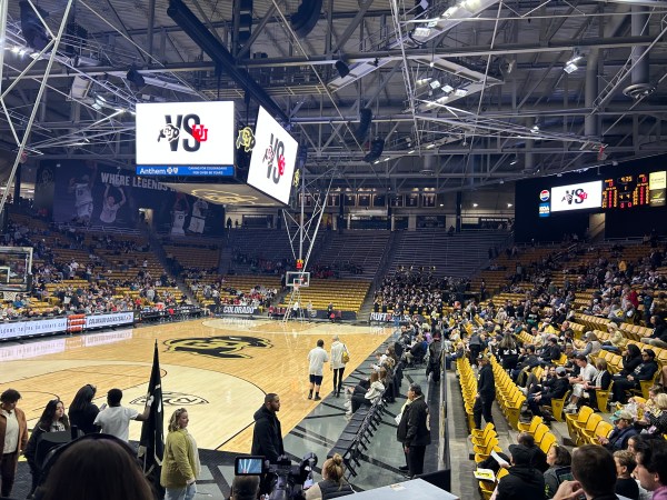 Yellow chairs line the indoor basketball court at CU Event Center. Large screens in the center display CU vs. UU.