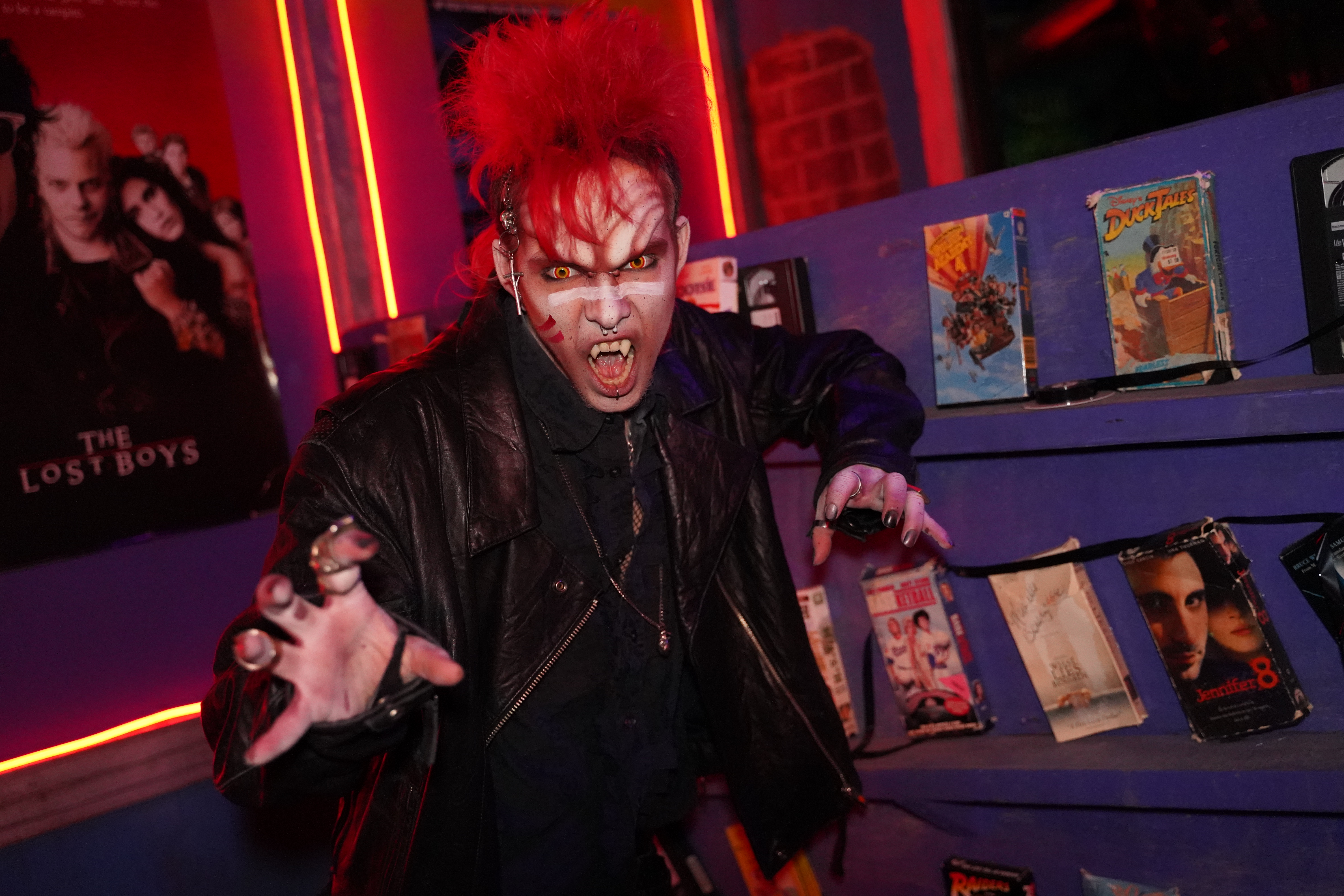 A person wearing vampire make up with a red mohawk makes a scary face in the haunted house.
