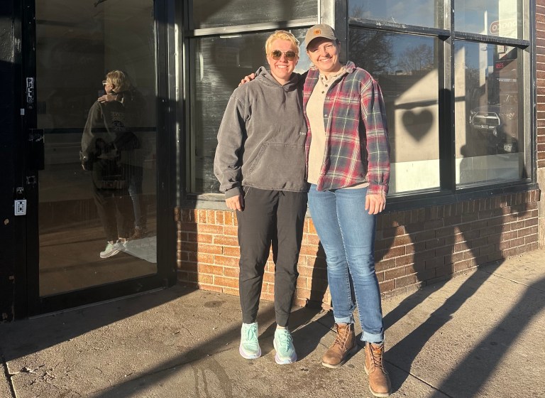 Two women stand in front of an empty store front.